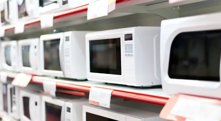 Историята и произхода на микровълновата печка 6 Рафтове, пълни с бели микровълнови печки за продажба в универсален магазин.